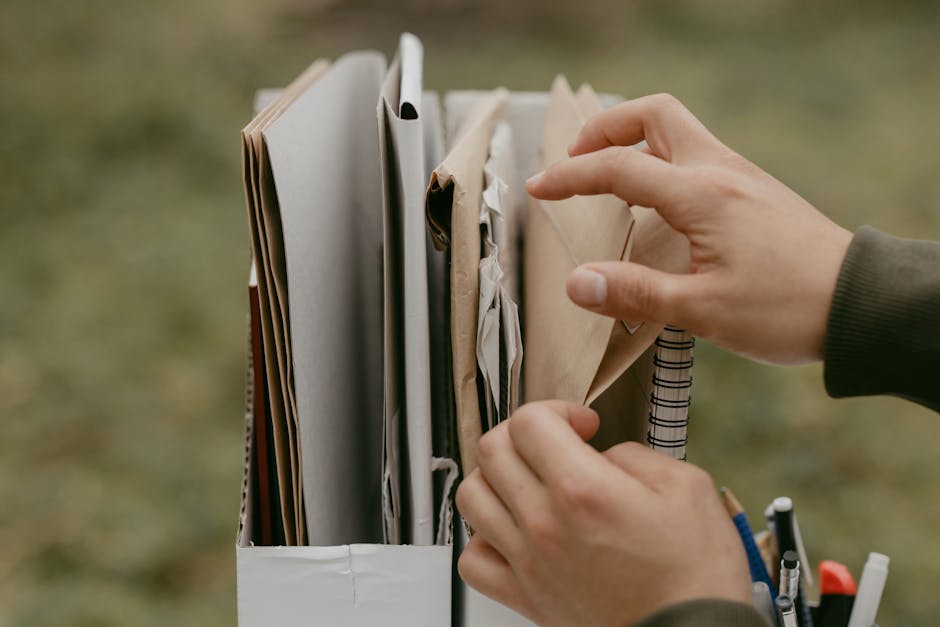 Hands organizing documents and envelopes, emphasizing office work and organization outdoors.