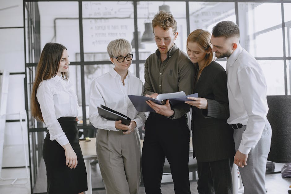 A diverse group of professionals collaborating and discussing documents in a modern office space.